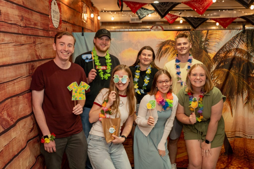 Group of adults posing or a photo with a tropical theme background