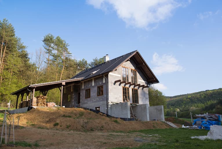 New house with unfinished roofing and forest backdrop