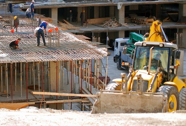 Workers and heavy machinery at a construction site.