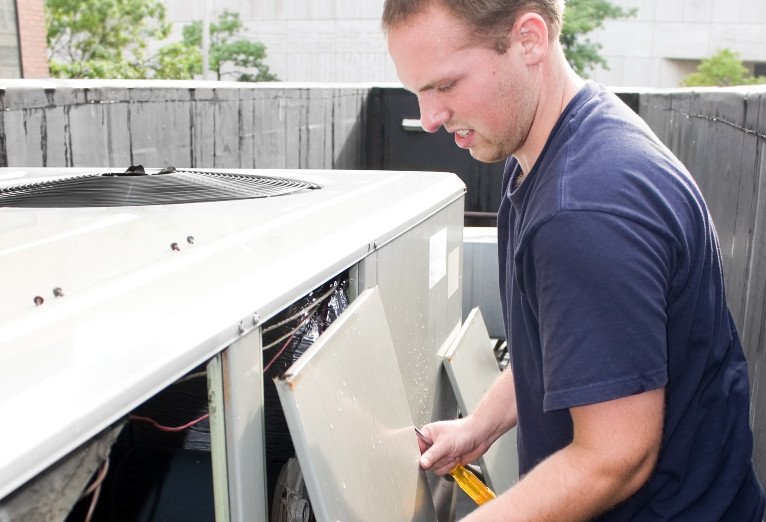 Technician repairing an outdoor HVAC unit.