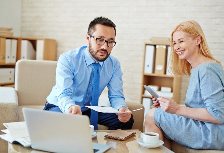 Business meeting with a man handing papers to a smiling woman.