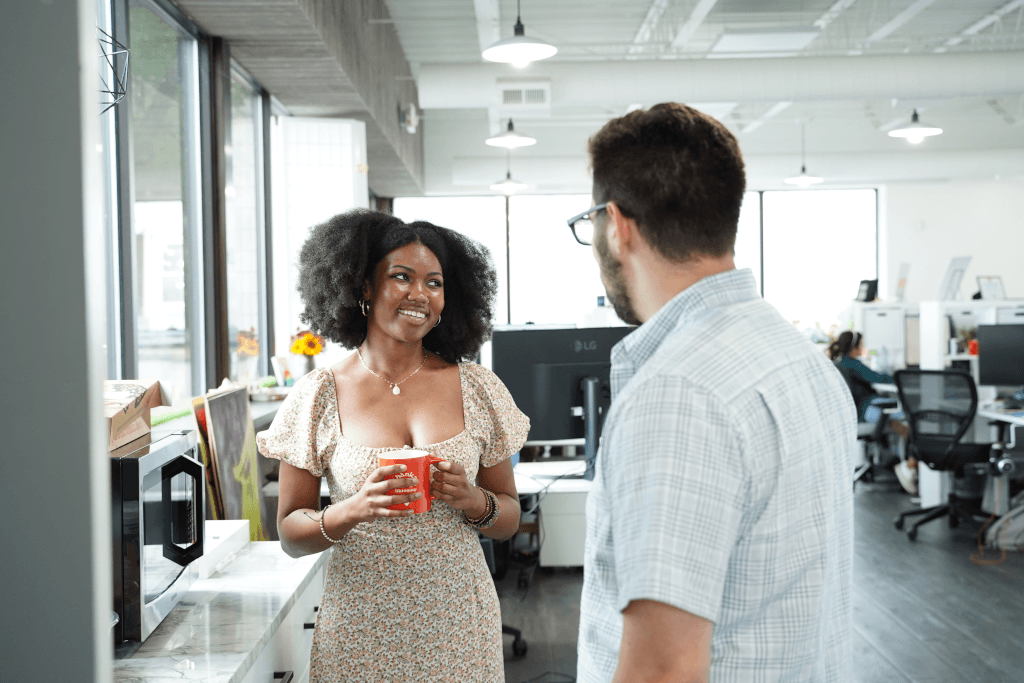 Dois colegas conversando com café em um espaço de escritório bem iluminado